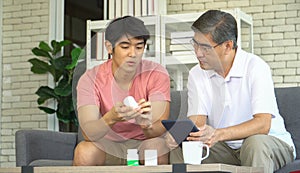 Asian Grown-up son explains medicine details to retired father listen