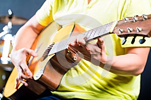 Asian guitarist playing music in recording studio