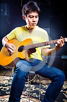 Asian guitarist playing music in recording studio