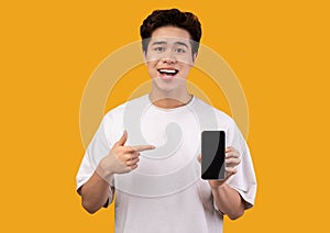 Asian guy showing blank smartphone screen and pointing