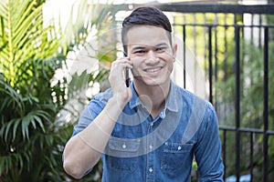 Asian guy wearing a comfortable dress talking on smartphone, Handsome guy smiles happy to talk