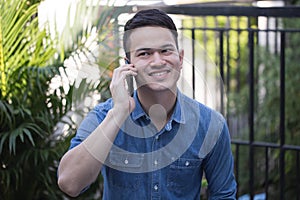 Asian guy wearing a comfortable dress talking on smartphone, Handsome guy smiles happy to talk