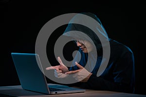 Asian hacker hacking computer network with laptop in dark. Cyber security concept