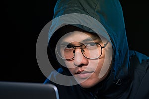 Asian hacker hacking computer network with laptop in dark. Cyber security concept