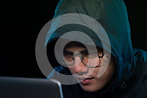 Asian hacker hacking computer network with laptop in dark. Cyber security concept