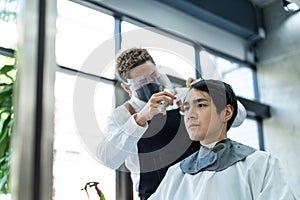 Asian hairdresser barber wear mask, cut hair of attractive man in shop. Handsome young man customer in modern salon barbershop,