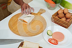 Asian hand close up Garnishing the egg sandwich After using a knife to cut a sandwich that was placed on a wooden chopping board.