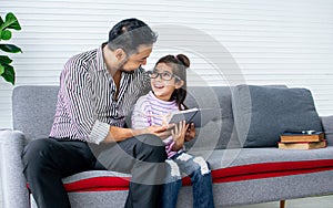 Asian handsome adult warm father and sweet cute little daughter girl sitting on sofa in living room at home, drawing, doing