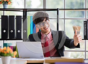 Asian handsome business working man wearing eyeglasses, red shirt with necktie, large smiling and making great thump up with