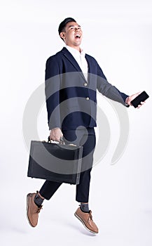 Asian handsome business working man wearing formal blue suit, holding black briefcase and mobile phone, jumping, shout out,