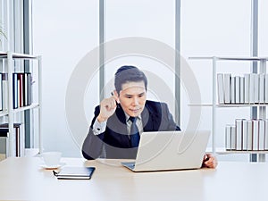 Asian handsome businessman in suit working with laptop computer on desk in office