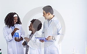 Asian handsome male teacher wearing eyeglasses and white gown uniform, teaching science and experiment to African black boy and