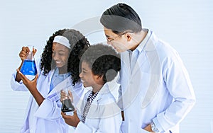 Asian handsome male teacher wearing eyeglasses and white gown uniform, teaching science and experiment to African black boy and