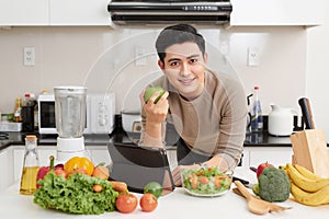 Asian handsome man looking recipe on laptop in kitchen at home