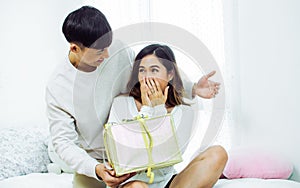 Asian handsome man making surprise and give a gift box to his girlfriend on valentine`s day or birthday. Lifestyle Concept
