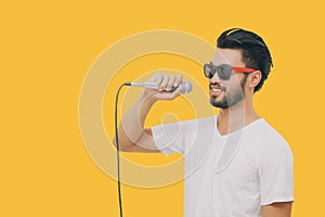 Asian handsome man with a mustache, smiling and singing to the microphone  on yellow background