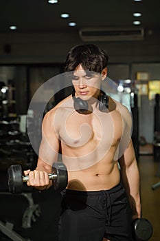 Asian handsome man with perfect body playing weight training at fitness center