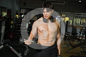 Asian handsome man with perfect body playing weight training at fitness center