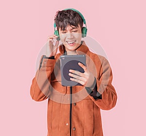 Asian handsome man smiling and listening music by big green headphones by smartphone search