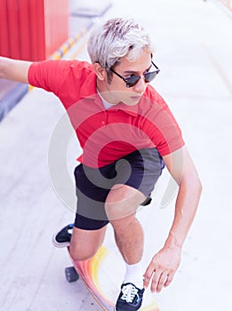 Asian handsome man surfing skateboard and abbreviate on skate board at skateboard street way in daylight time, summer holiday photo