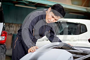 Asian handsome mechanic man in uniform working with car parts engine vehicle, auto mechanic technician inspecting maintenance