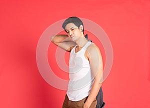 Asian handsome young man with big muscle wearing white vest hand hold take off shirt standing isolated on red background shot in