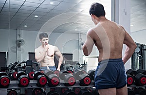 Asian handsome young muscular asian man exercising bodybuilder  in front of a glass in the gym .Guy flexing trains his bicep