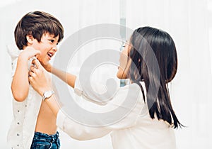 Asian happy beautiful mother getting dressed clothes on her kids photo