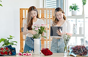 Asian happy cheerful female florist flower shop owner holding pink roses bouquet decorating in white ceramic vase for customer