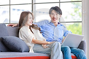 Asian happy cheerful joyful husband and wife lover couple family sitting smiling cuddling together on cozy sofa couch watching