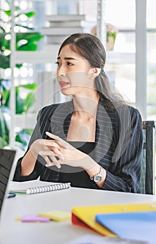 Asian happy cheerful professional successful female businesswoman employee in formal suit sitting smiling holding hands up