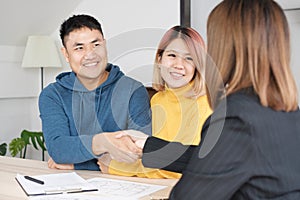 Asian happy couple getting key and handshake with realtor agent with smiling face at new home.buying new house real estate