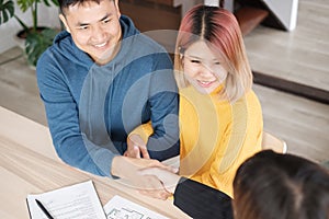 Asian happy couple getting key and handshake with realtor agent with smiling face at new home.buying new house real estate