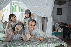 Asian happy family and child daughter relaxing on the bed