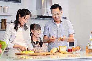 Asian happy family, Mother cook food for dinner in kitchen at house. Loving Father and young little kid daughter have fun spending