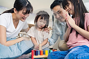 Asian happy family sit on floor, play kid toy together in living room. Attractive parents mother and father spend time with young