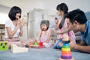 Asian happy family sit on floor, play kid toy together in living room. Attractive parents mother and father spend time with young