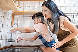 Asian happy family stay home in kitchen, mother spend time with little kid daughter together. Supportive loving mom teach young pr