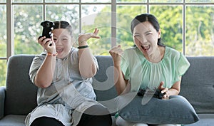 Asian happy funny lovely mother and young chubby down syndrome autistic autism little cute daughter sitting on cozy sofa smiling