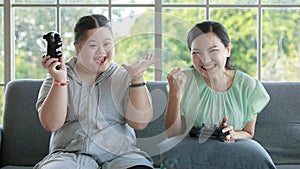 Asian happy funny lovely mother and young chubby down syndrome autistic autism little cute daughter sitting on cozy sofa smiling