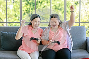 Asian happy lovely mother and young chubby down syndrome autistic autism little daughter sitting on cozy sofa wearing VR virtual