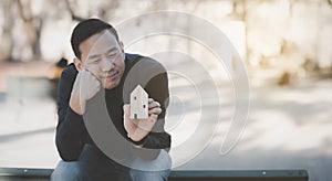 Asian happy Man hand choosing mini wood house model from model on wood table, Planning and buy Real Estate, Planning to buy proper