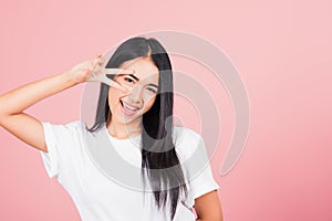 Asian happy portrait beautiful cute young woman teen smile standing showing finger making v-sign victory symbol near eye