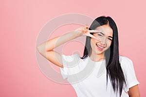 Asian happy portrait beautiful cute young woman teen smile standing showing finger making v-sign victory symbol near eye