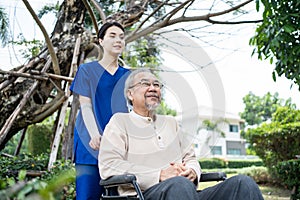 Asian happy Senior retired grandfather have fun outdoor at green park with young woman nurse. Caregiver doctor take care, pushing