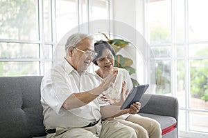 An Asian happy seniors elderly are video calling , relax at home, smiling healthy senior retired grandparents, older grandparent