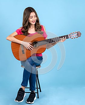 Asian happy singer woman sit on bar chair and sing a song with acoustic guitar