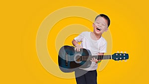 Asian happy smiling boy having fun playing guitar isolated on colored background, Music for kids and toddlers concept