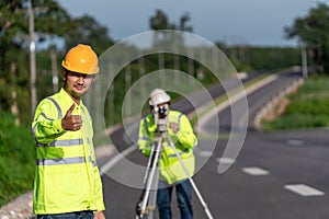 Asian happy surveyor engineers with digital level looking at camera on road construction site, Civil Engineers, Surveyor equipment