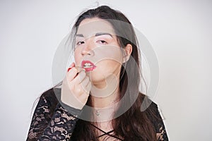 Asian happy woman paints her lips with lipstick on white studio background. Wrong try to do good self make up. Adult girl is learn